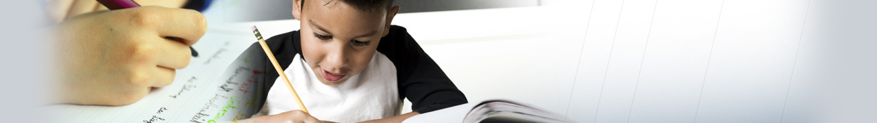 left centered header of young boy writing in a journal; close up of hand holding pen to paper in left corner