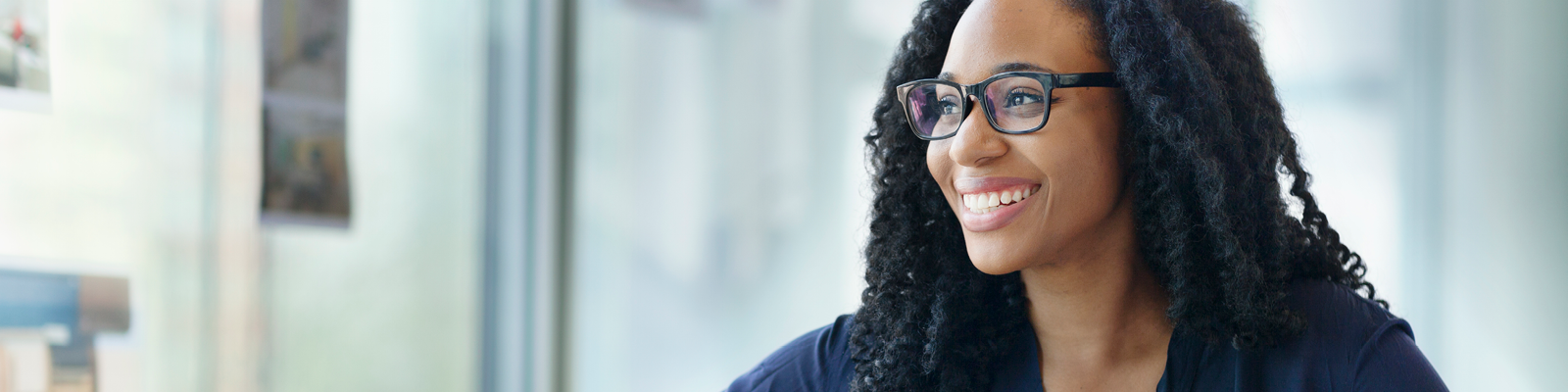 Young professional woman wearing glasses and smiling while envisioning her future