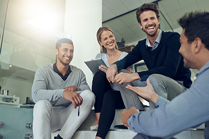 group of coworkers talking together while sitting on some stairs in an office