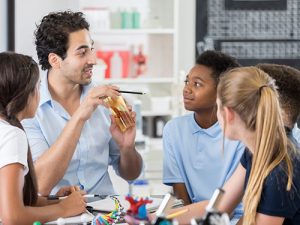 Science teacher at table with young students