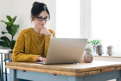 Woman sitting at table, using laptop