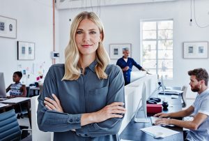 Portrait of confident businesswoman in office with staff in background