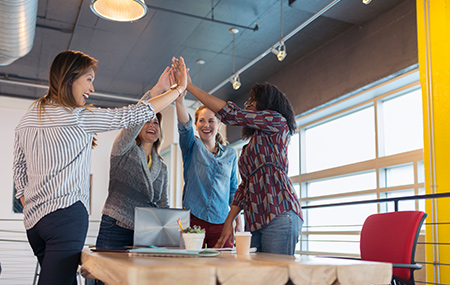 Businesswomen high fiving in conference room