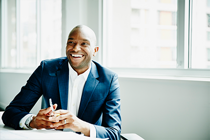 Smiling businessman in discussion at workstation in office