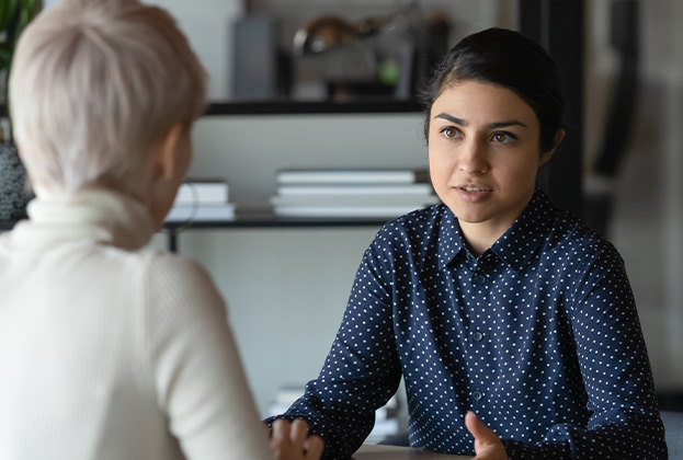 Businesswomen discussing project while seated at office workstation