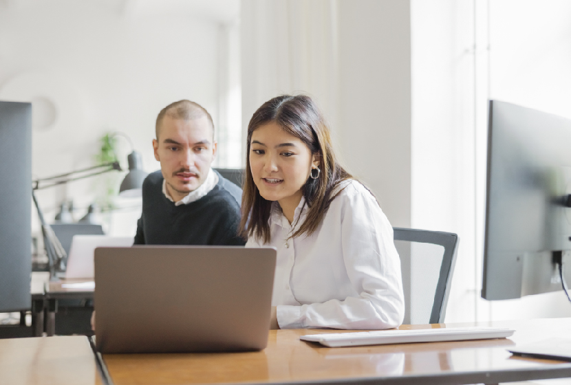 Boss providing a micromanagement style of leadership over an employees shoulder in the office
