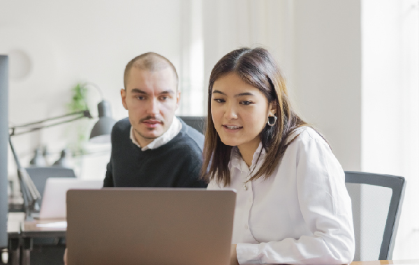 Boss providing a micromanagement style of leadership over an employees shoulder in the office