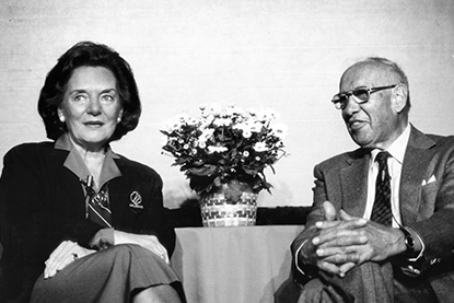 Black and White photo; Peter Drucker Frances Hesselbein with wife sitting at a table; hands folded