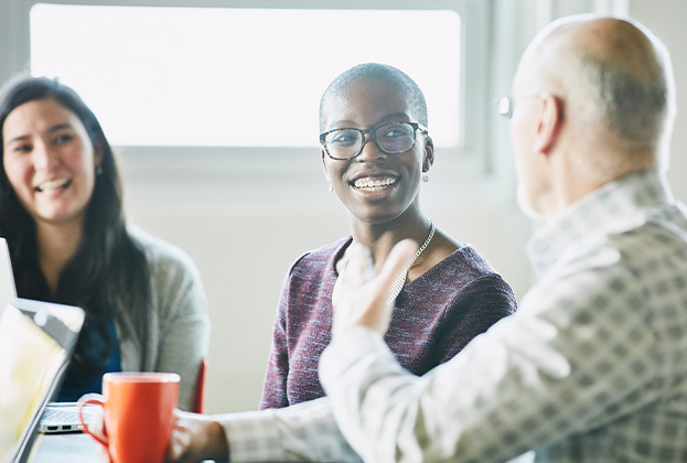 Smiling businesswoman in discussion with colleague during meeting in conference room