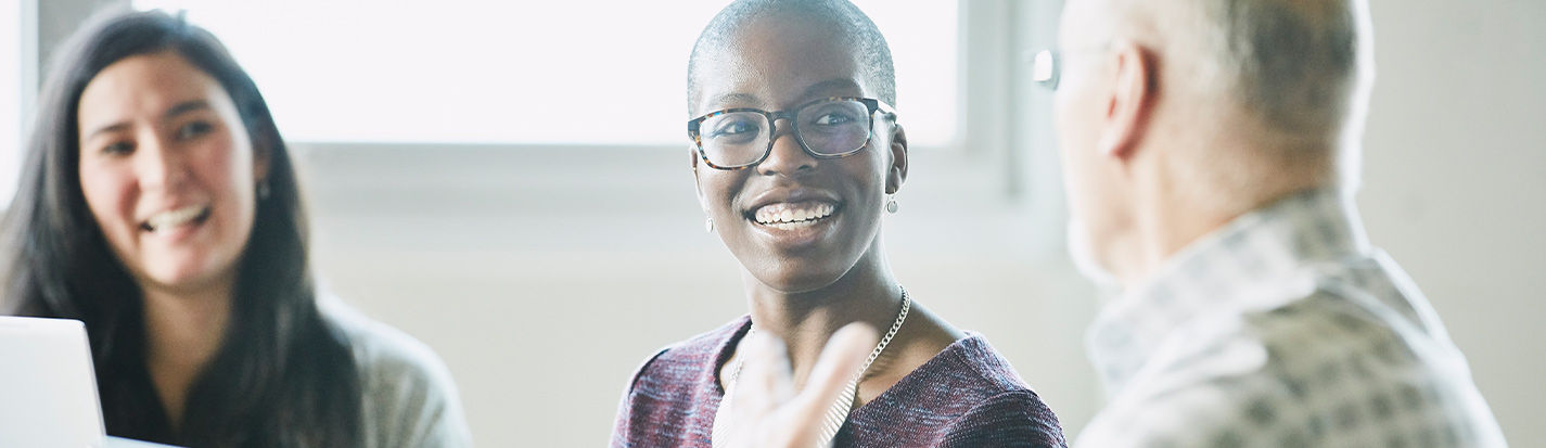 Smiling businesswoman in discussion with colleague during meeting in conference room