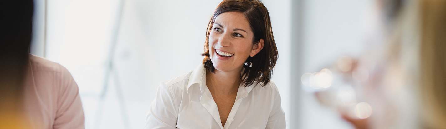 Cheerful mid adult woman smiling at business meeting