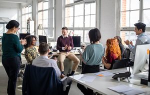 Group of business people clapping hands for a coworker in staff meeting