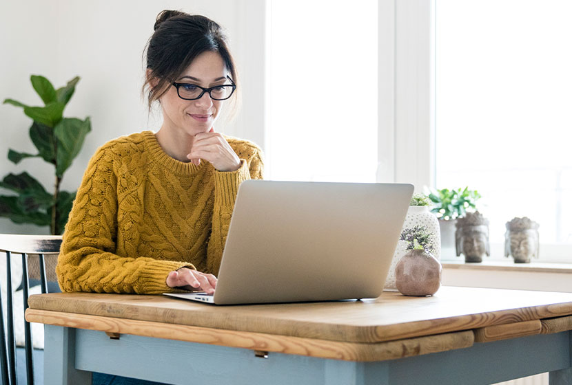 Woman sitting at table, using laptop