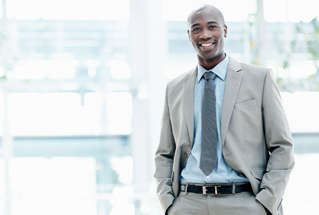 Smartly dressed executive smiling as he stands at his workplace