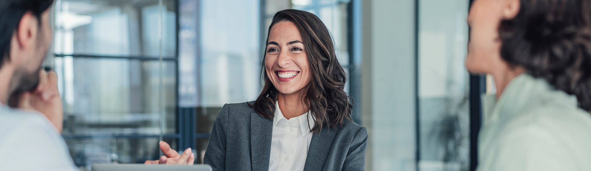 Businesswoman laughing and smiling with coworkers in a conference room.