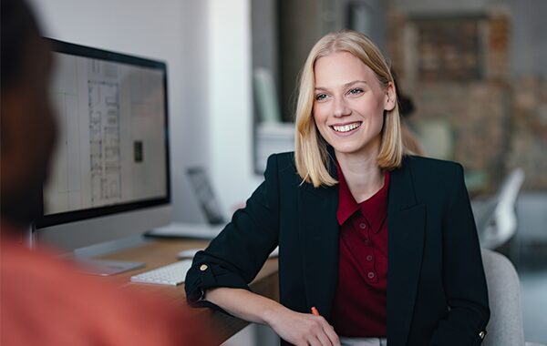 A smiling coworker speaking with a colleague.