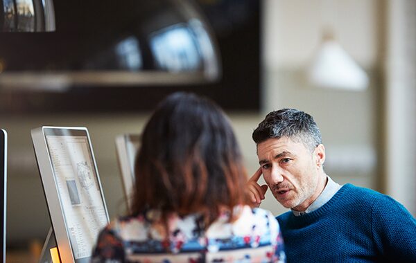 Two coworkers engaged in a conversation at their desk