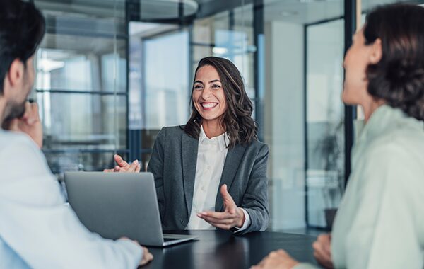 Businesswoman laughing and smiling with coworkers in a conference room.