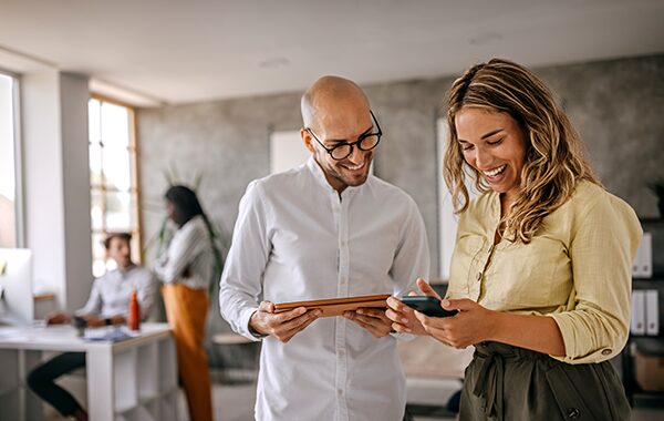 Two coworkers looking at a device together in an office