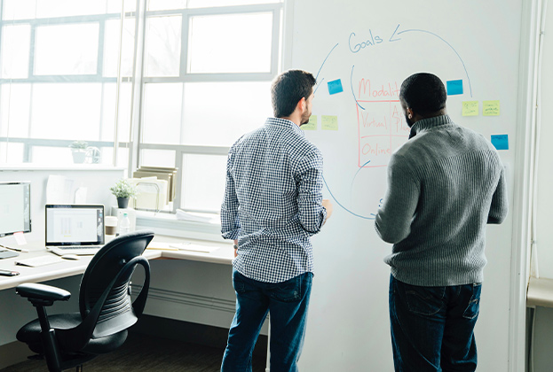Businessmen using whiteboard in office