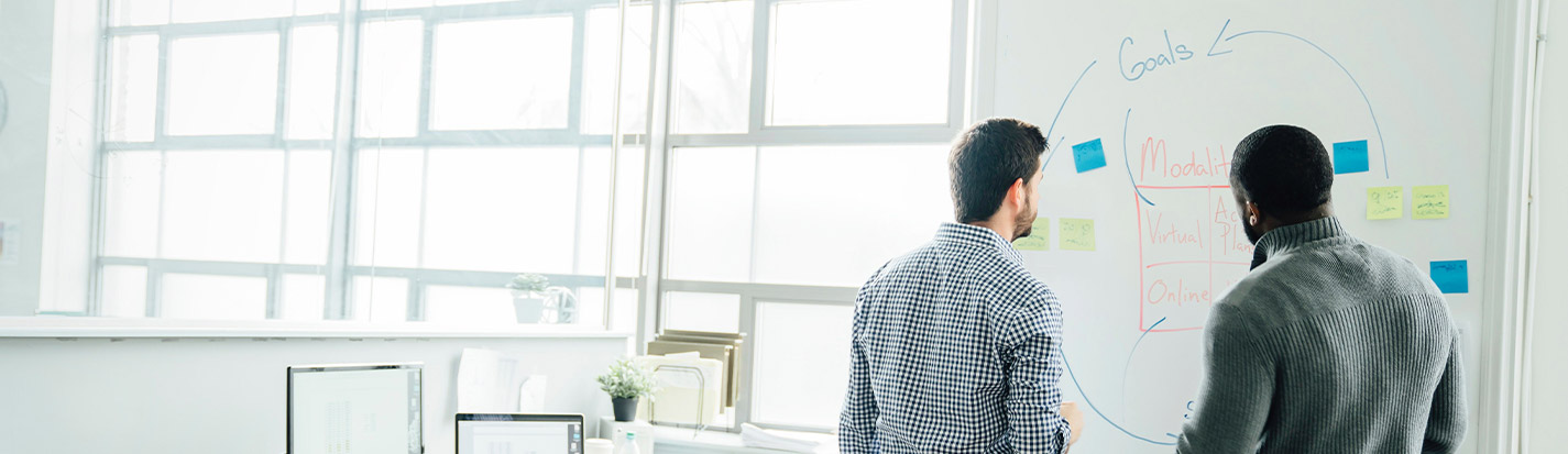 Businessmen using whiteboard in office