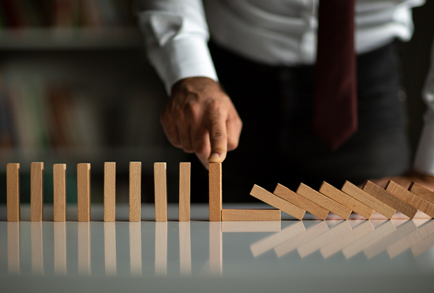 Businessman Stop Domino Effect. Leadership and Crisis Management Concept